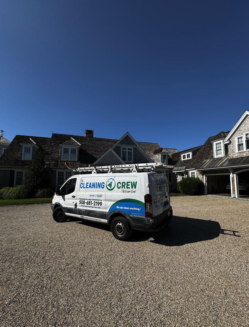 Crew van on a gravel driveway at a large shingled home